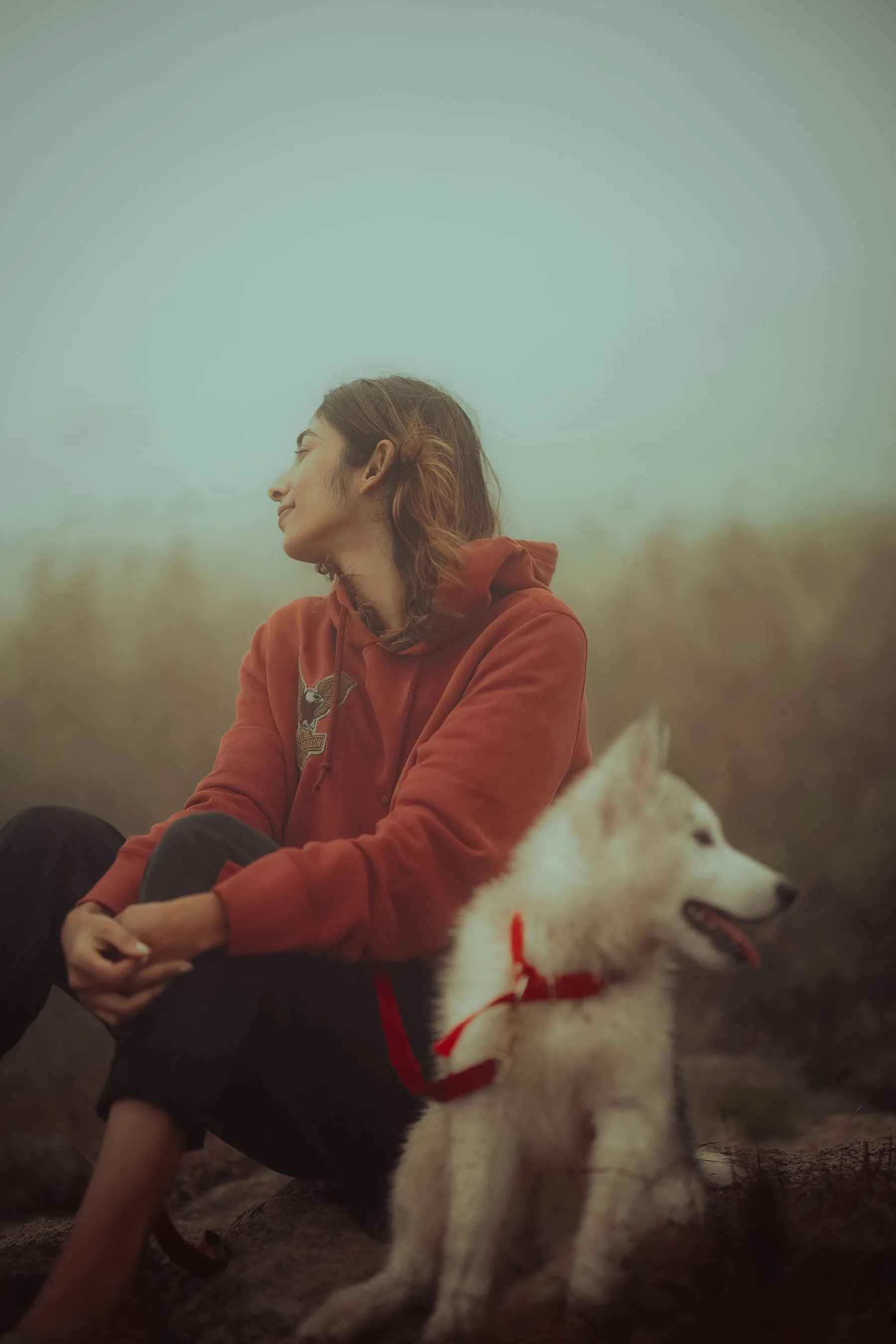 Woman sitting outdoors beside her Husky puppy